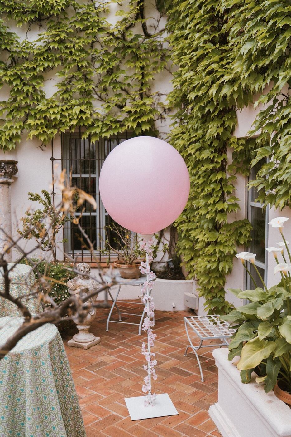 Single pink balloon on blossom-wrapped stand in a courtyard, Finca Santa Katerina