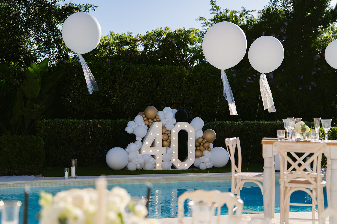 Giant light-up 40 numbers with black, white and gold balloon cluster beside a pool, Marbella villa