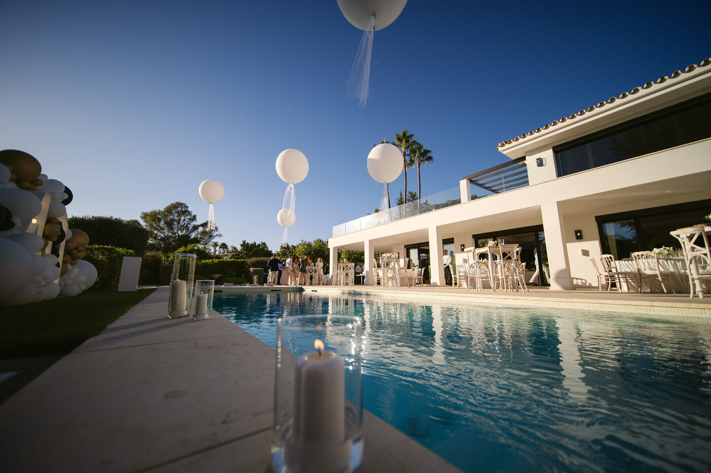 Luxury Marbella villa pool with jumbo round balloons and guests at dusk