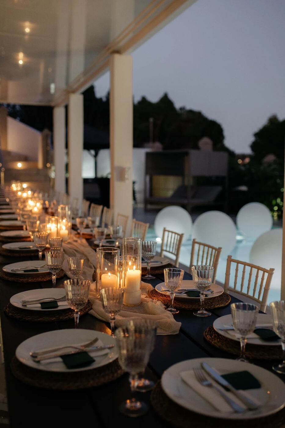 Candlelit dinner table with pool balloons in the background