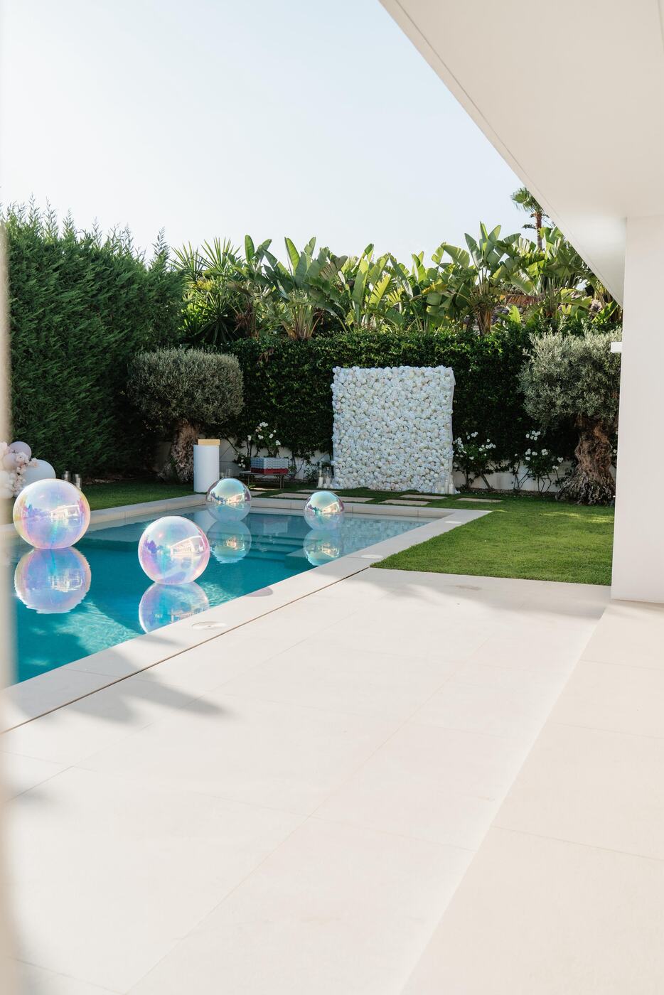 White flower wall backdrop beside a pool with floating iridescent orbz, Marbella villa