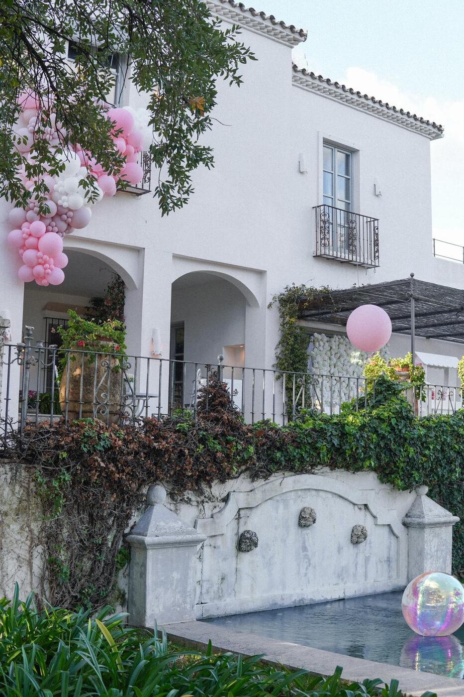 Pink and white balloon garland cascading down a villa facade with a giant pink balloon, Marbella
