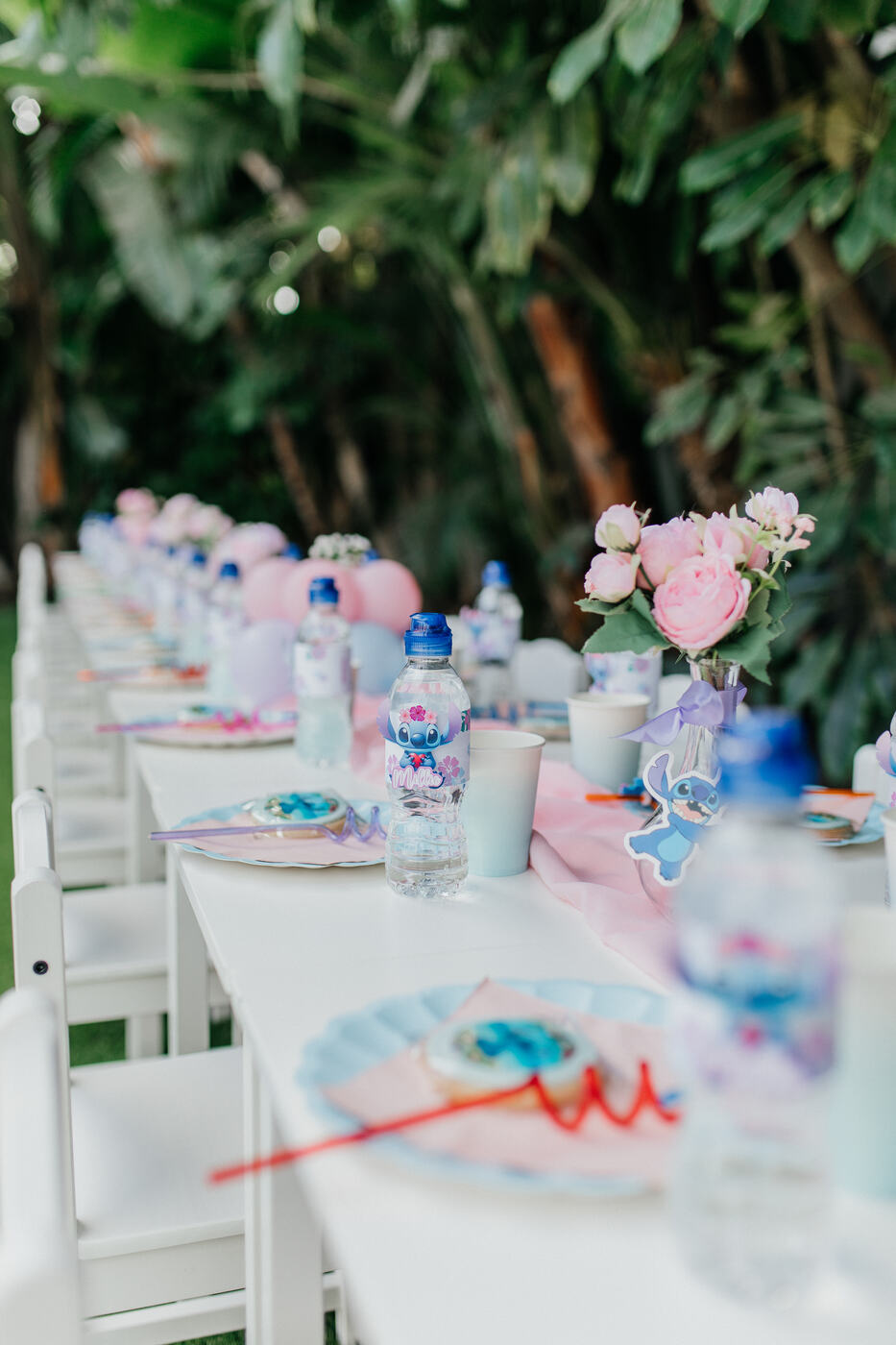 Kids' party table with personalised Stitch water bottles and pink peonies, Marbella